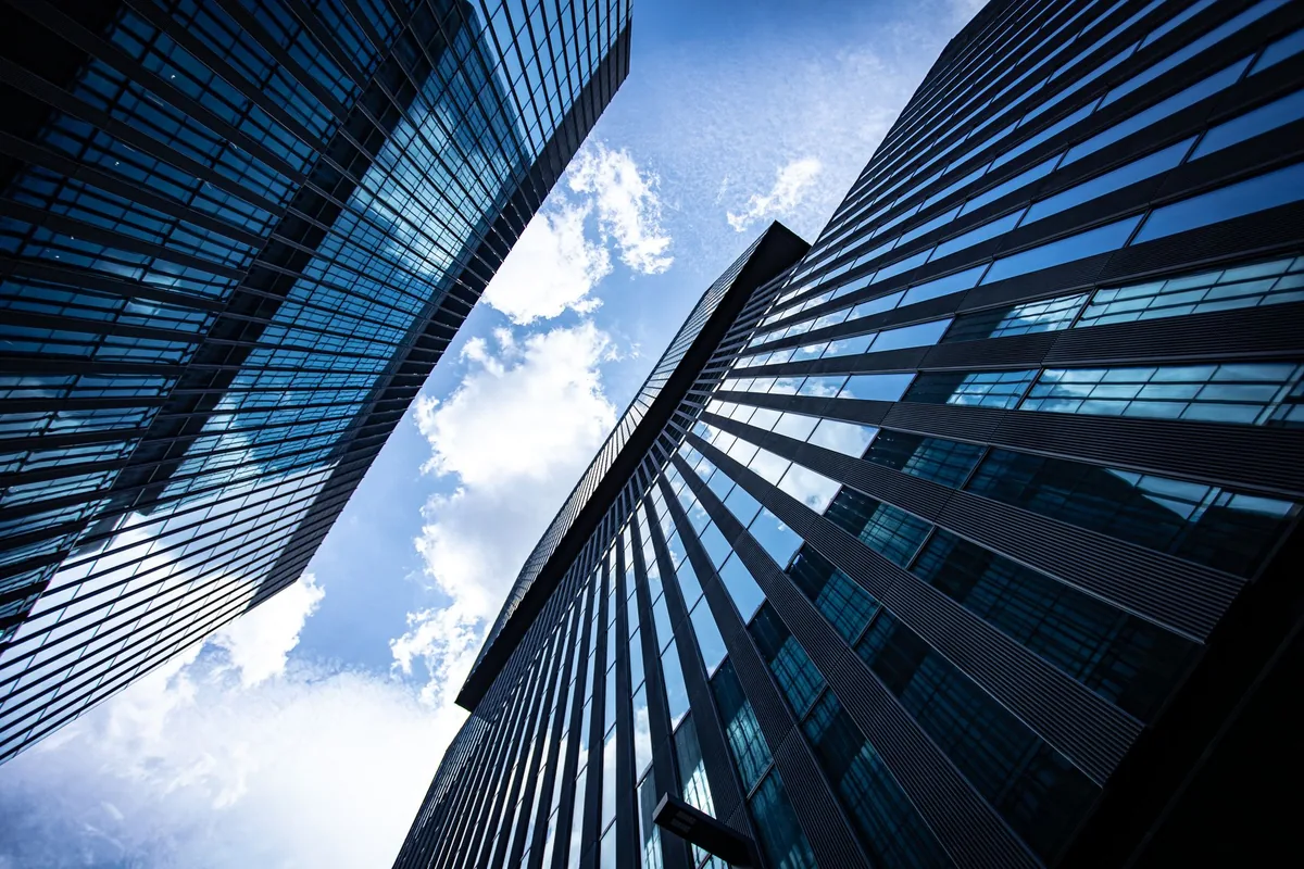 Glass office towers photographed looking upward against a blue sky