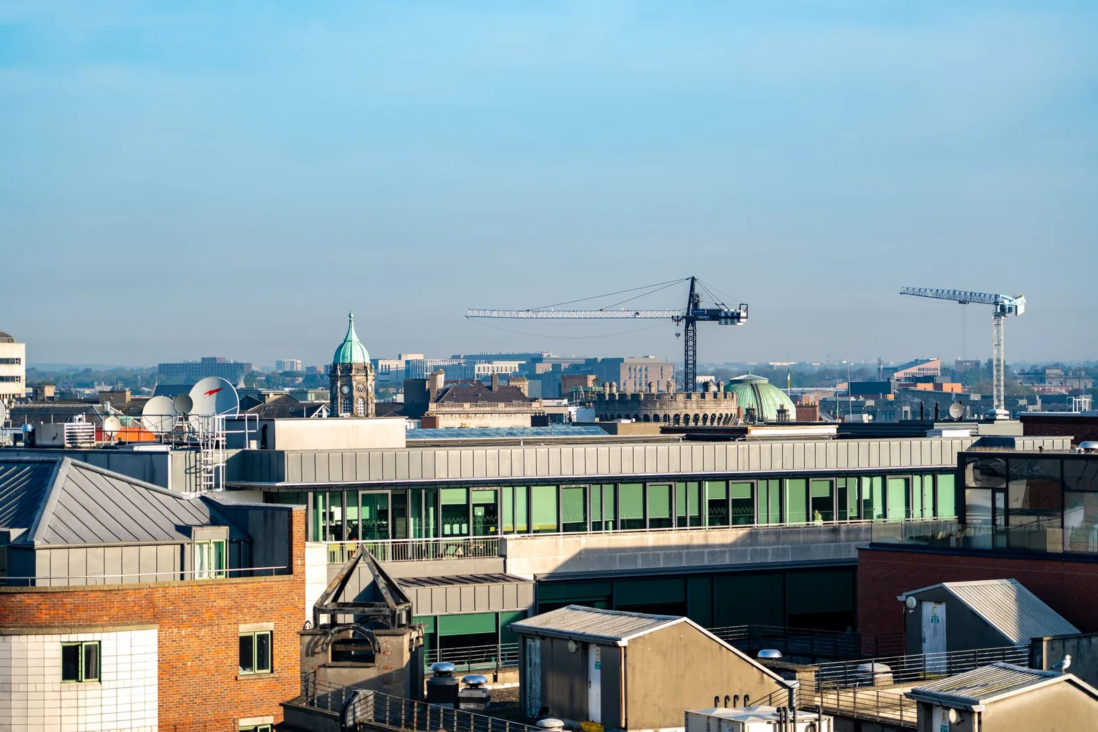 A city skyline with construction cranes above the rooftops