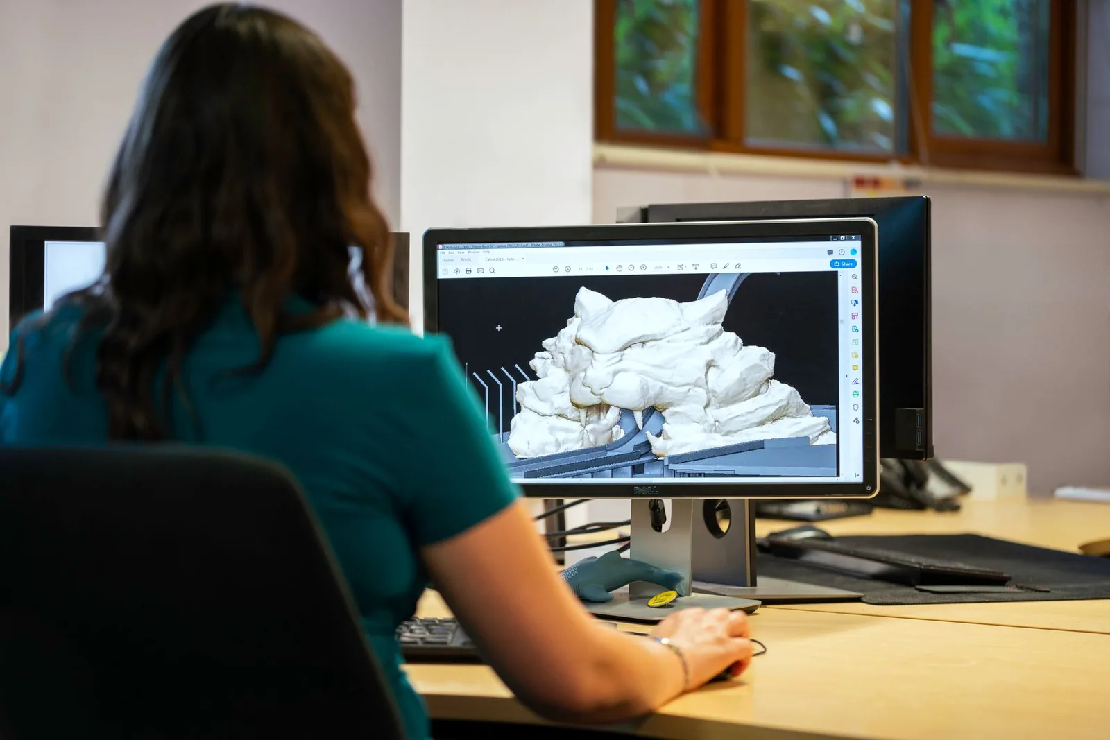 A designer modelling a three-dimensional object on a large monitor